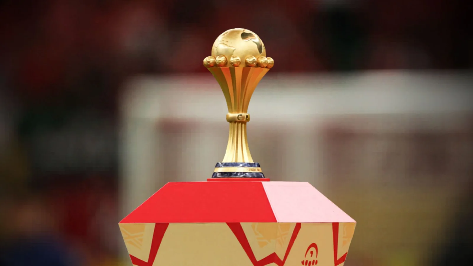Le trophée de la Coupe d’Afrique des nations posé sur un socle rouge et doré